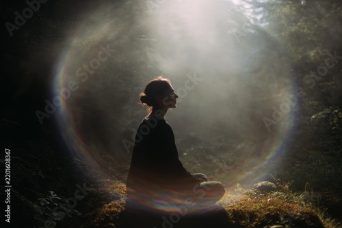 Person meditating inside a visible auric light ring in forest clearing for wellness background and mindfulness poster design