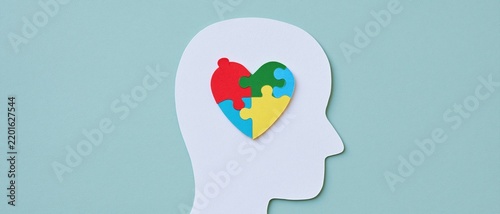 Human head silhouette with colorful puzzle heart on pastel blue background