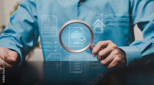 Document review and compliance. Professional using a magnifying glass to inspect digital records, forms, tax information, checklist, property data, and verification documents online.