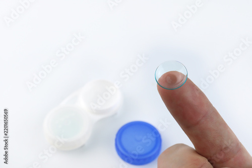 Obraz na płótnie Close-up of a soft contact lens resting on fingertip with lens case softly blurred in background