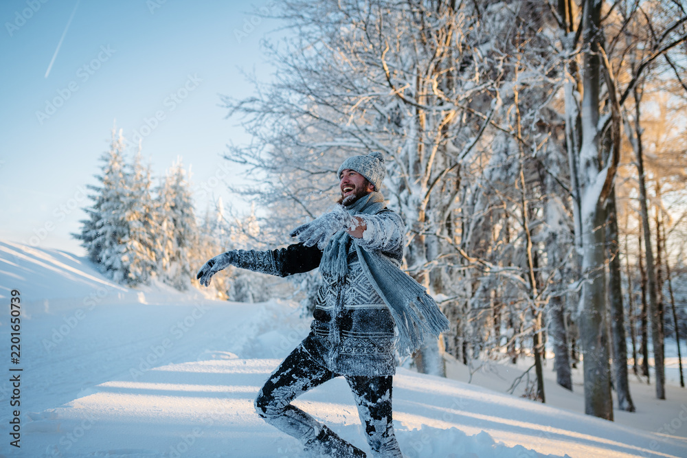 Obraz premium Playful man covered in snow enjoying winter fun in snowy woodland.