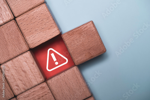 Red warning symbol revealed among wooden blocks represents hidden risk, danger problem detection and crisis alert with copy space for business security, prevention and risk management concepts.