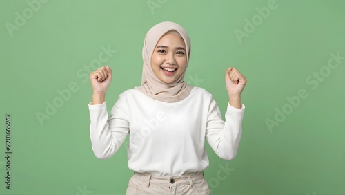 Excited young Muslim woman in hijab celebrating success with joy