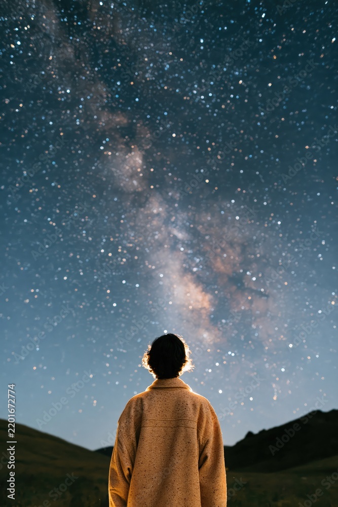 Fototapeta premium Person silhouetted under the milky way night sky in remote landscape for astronomy wallpaper and stargazing background design