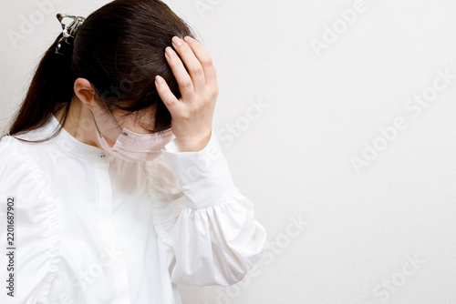 Naklejka マスクをした女性 額に手をあててうつむく様子