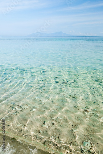 Crystal clear shallow tropical water with sun caustics on sandy seabed in Timor Leste