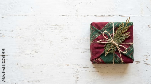 Zero Waste Christmas Gift Wrapped in Fabric Furoshiki Style with Twine Bow on White Rustic Wood with Copy Space