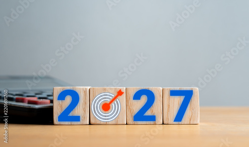 2027 goal and business target concept with target icon on wooden blocks and calculator
