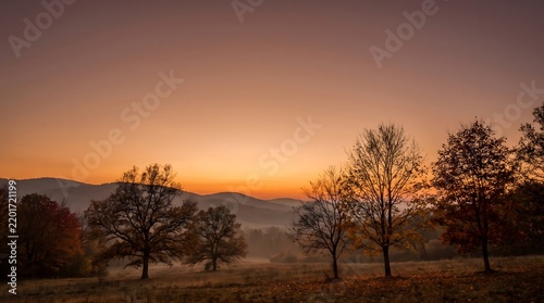 Autumn Mountain Landscape At Sunset With Rolling Hills Colorful Forest Golden Foliage Winding Road And Warm Orange Sky Nature Scenery