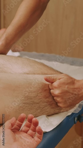 thumb and forearm pressure knead upper thigh and hamstring on padded table in quiet spa clinic with warm light