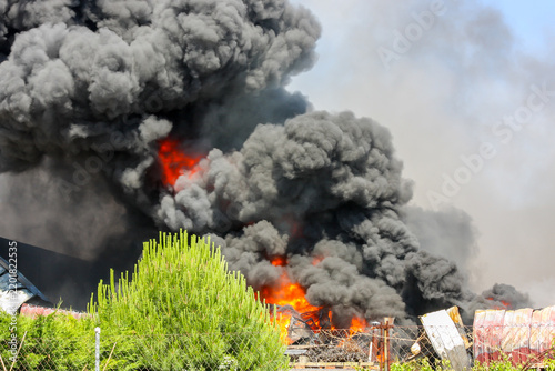 Industrial factory fire creating thick black smoke pollution