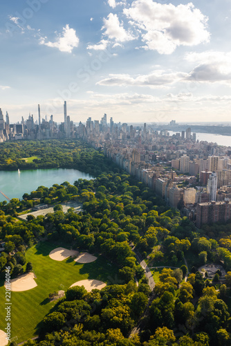 Aerial view shows Central Park featuring baseball fields and the Jacqueline Kennedy Onassis Reservoir beside the Manhattan skyline along the Hudson River in New York.