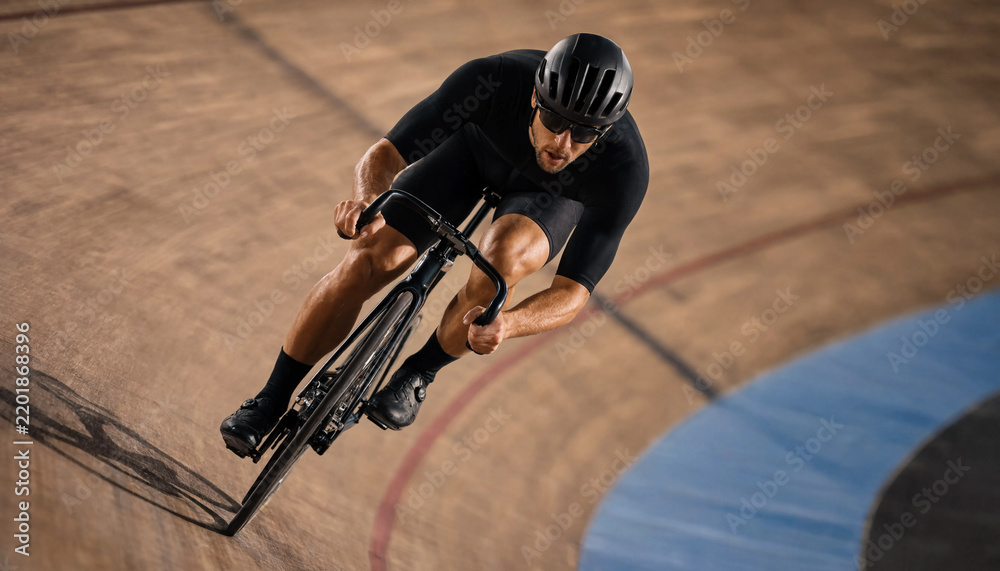 Obraz premium Male cyclist riding fast on fixed gear bicycle during intense track cycling training at wooden indoor velodrome. Concept of athlete, bike. Copy space.