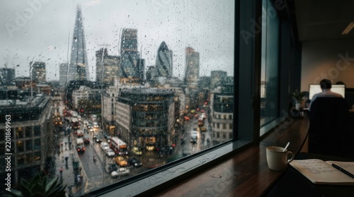 View of the London City skyline through an office window on a rainy day with a person at a desk back