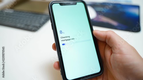 Hand holding smartphone with app checking mortgage rate and showing rate locked confirmation