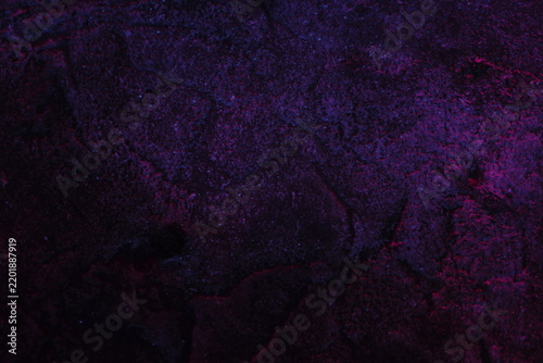 Abstract textured surface with purple and deep blue tones illuminated by artificial light
