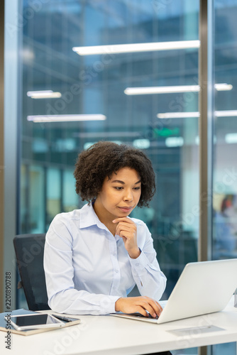 Businesswoman working on laptop in office, professional woman using computer for financial analysis and corporate tasks at desk with focus and concentration