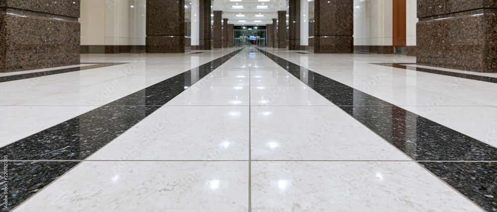 Obraz premium Low angle view of polished marble and granite tiled floor in a corporate lobby hallway