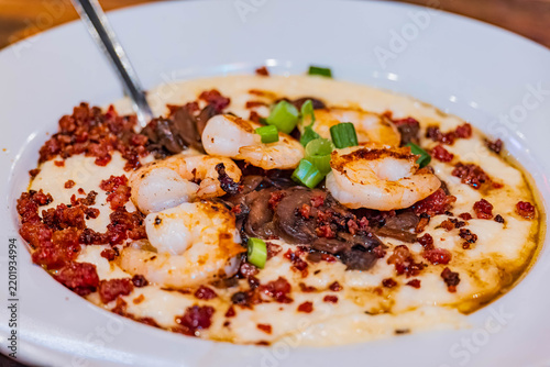 Savory shrimp and grits are served in a white bowl.