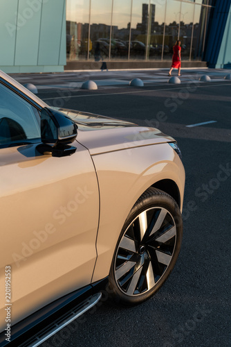 Close up of a beige luxury SUV parked on a city street during the golden hour sunset light