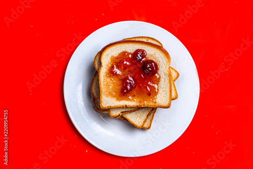 Toast with Berry Jam on White Plate Against Red Background