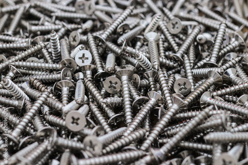Konstfotografi Close up of a large pile of new stainless steel screws with cross recess countersunk heads and sharp coarse threads, a metal fastener background for construction and hardware supply