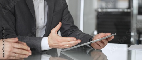 Business colleagues collaborating on a digital tablet, discussing data and financial insights during an office meeting, symbolizing technology integration and professional partnership, close up