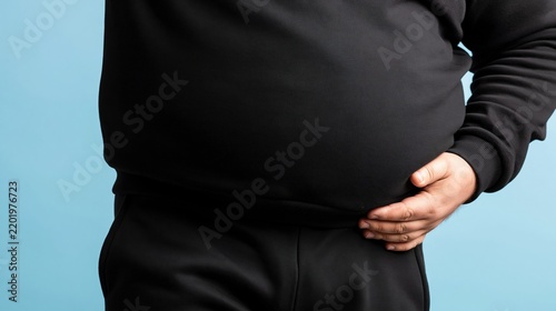 Overweight man in black sweatshirt holding his stomach. Close up of male midsection representing obesity and weight gain. Men health and fitness concept