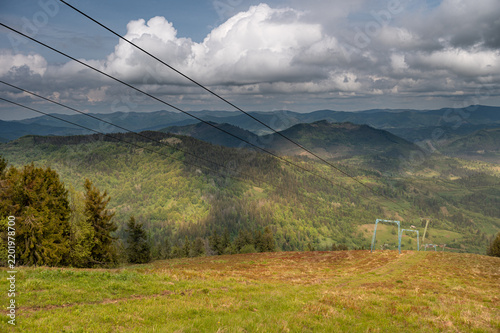 Ski lift cables above a green mountain landscape