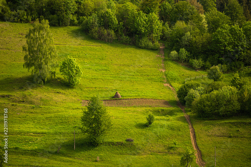 Rural meadow with haystack and winding dirt path