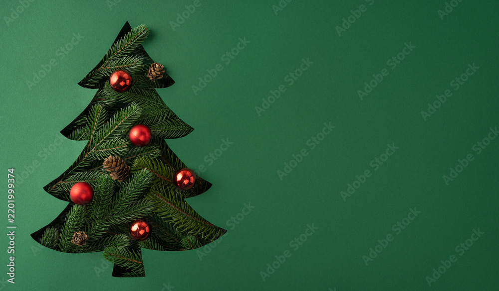 Fototapeta premium Merry Christmas and Happy New Year creative vision with cutout Christmas tree and red ornaments on banner green background