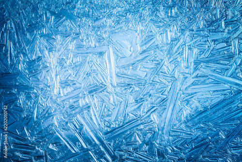 Ice frozen in intricate patterns of delicate crystals with brilliant contrasts of deep blues. Real unique patterned crystal formations. Sparkling window frost or icy cold winter frosting background.