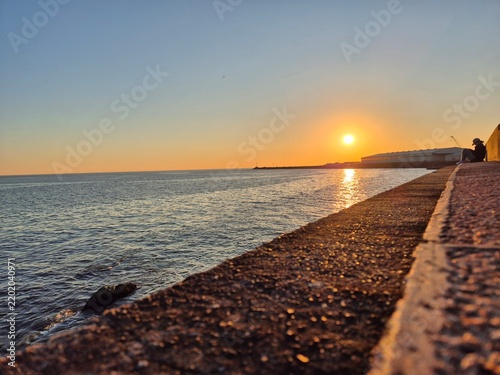 Bild auf Leinwand Golden sun setting over the Rio de la Plata with warm reflections on the water, viewed from the Rambla waterfront in Montevideo, Uruguay