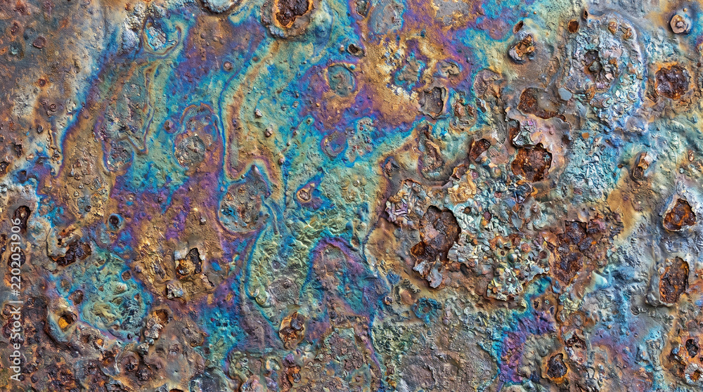 Obraz premium Iridescent oil slick on a weathered rusty metal surface with colorful chemical patterns and texture