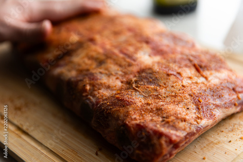 seasoning being rubbed onto a rack of beef ribs