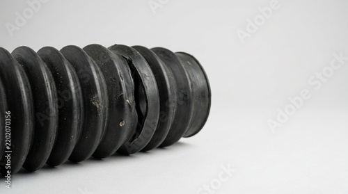 Torn rubber pneumatic cylinder bellows on neutral background