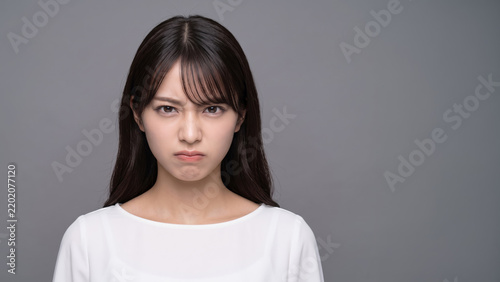 不満そうな表情でこちらを睨む若い女性