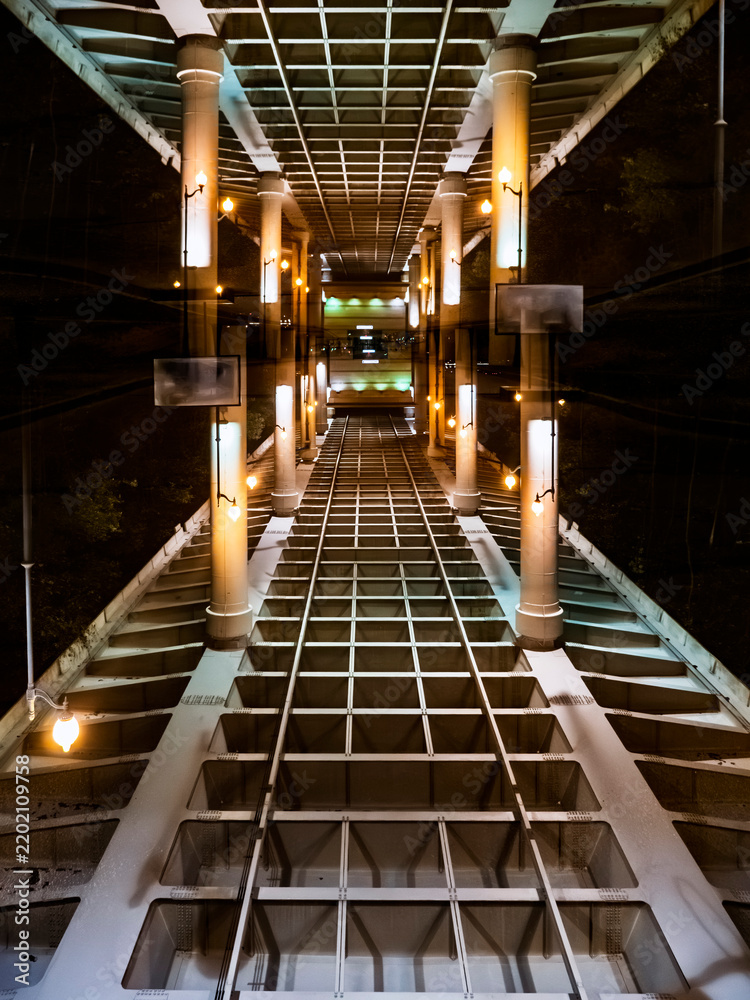 Obraz premium Symmetric architectural view of bridge structure at night with glowing lantern streetlights and metal girders in perspective