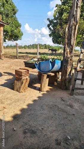 Konstfotografi Rustic backyard scene with repurposed blue barrel planter and stacked bricks