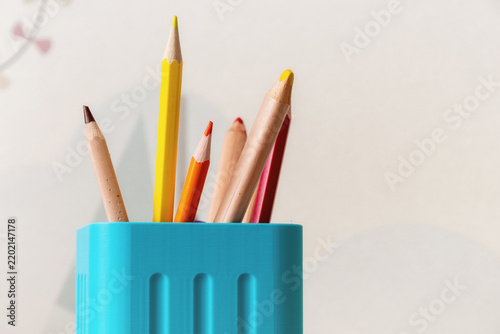 Sharpened colored pencils in a turquoise holder. Minimalist desk organization for education, art supplies, and creative workspace projects