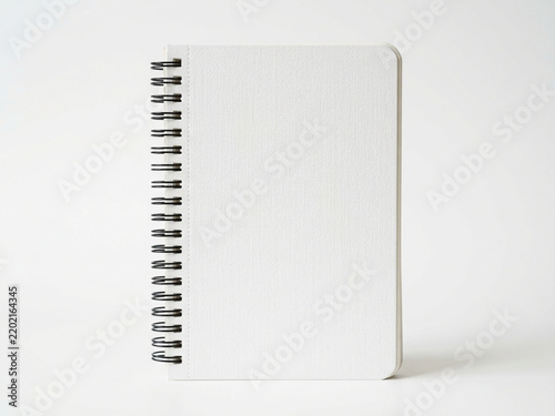 A spiral bound paper notebook rests upon a wooden desk surface waiting for creative thoughts, daily schedule entries, or educational study notes written down by hand during productive hours