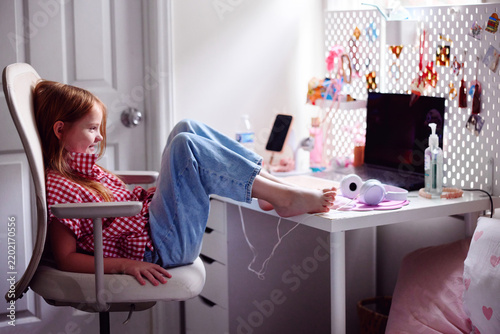 Happy girl relaxing at computer desk in cozy bedroom after school