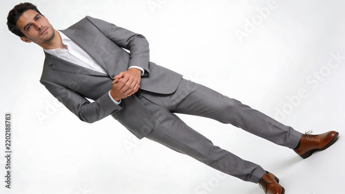 Man in gray suit and brown dress shoes posing dynamically against white studio background