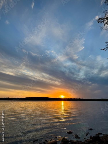 Cuadro en lienzo Beautiful golden sunset over a calm lake with dramatic clouds reflecting the warm evening light