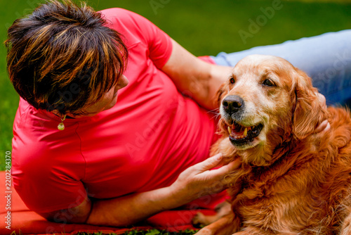 Woman relaxing with golden retriever dog in grass