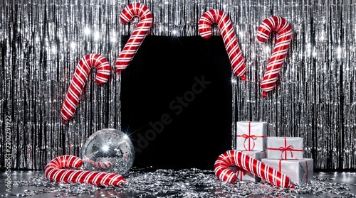 Festive holiday photo booth backdrop featuring a sparkling silver tinsel curtain, floating red and white candy cane balloons, a disco ball, silver gifts. Perfect for New Year's Eve party invitations