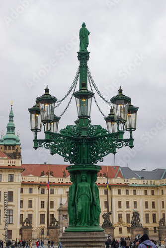 The historic ornate green cast-iron gas street lamp with caryatids and lanterns on Hradčany Square outside the Prague Castle complex.