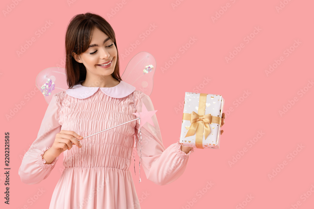 Obraz premium Young woman in fairy costume with wand and gift box on pink background
