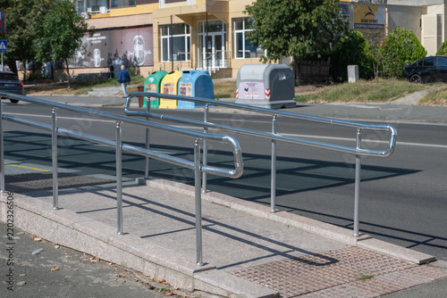 Obraz na płótnie A concrete accessibility ramp fitted with shiny stainless steel handrails leads safely to an urban pedestrian sidewalk alongside a city street
