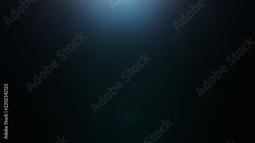 dust particles floating mid air over dark background with some lens flare